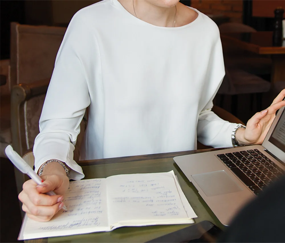 Person with laptop and notebook writing notes, representing document preparation services in Santa Barbara